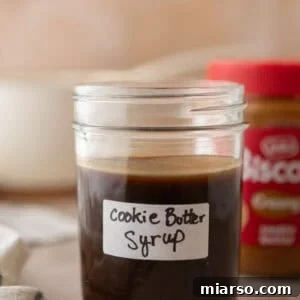 Homemade cookie butter coffee syrup in a labeled mason jar with a jar of Lotus Biscoff cookie butter in the background.