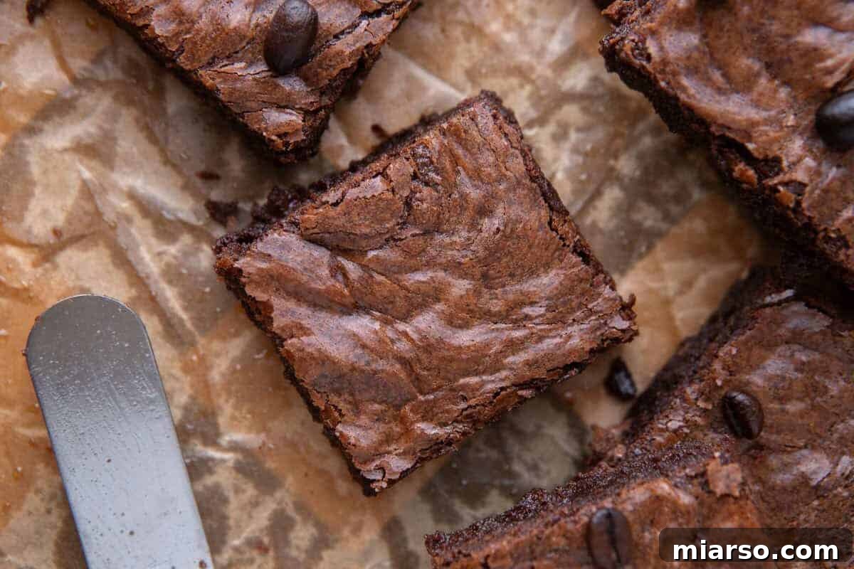 Espresso Fudge Brownies 2 Fudgy espresso brownie square on crinkled parchment paper with an offset spatula
