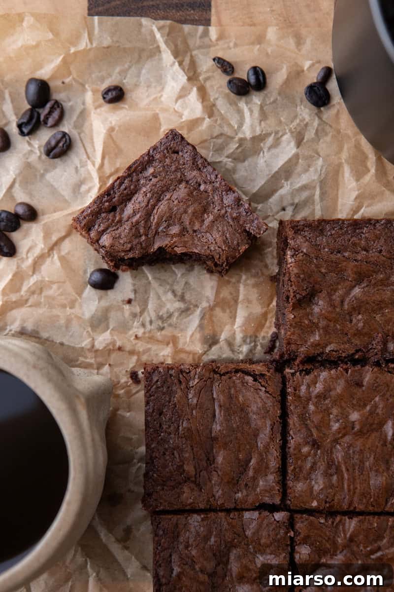 Espresso Fudge Brownies 14 Overhead shot of sliced brownies on parchment with scattered coffee beans and a ceramic mug of espresso