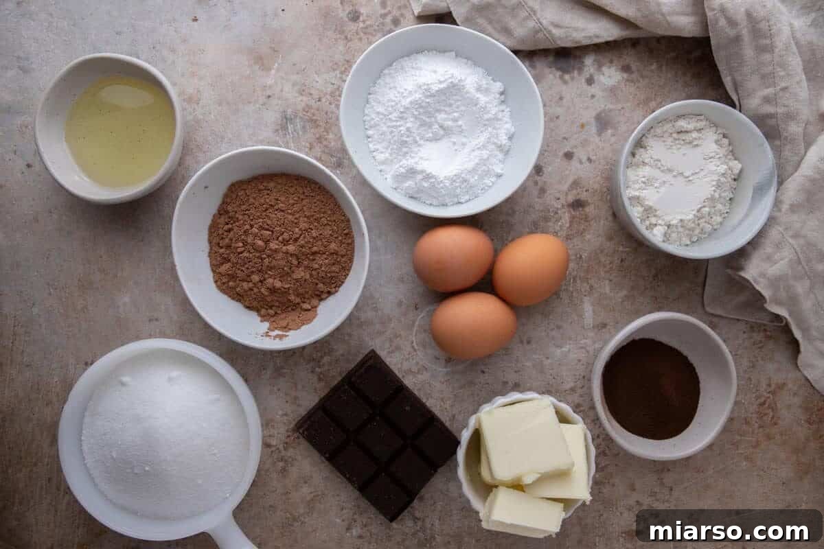 Espresso Fudge Brownies 4 All ingredients for espresso brownies measured in white bowls including cocoa powder, dark chocolate bar, eggs, butter, sugar, and espresso powder