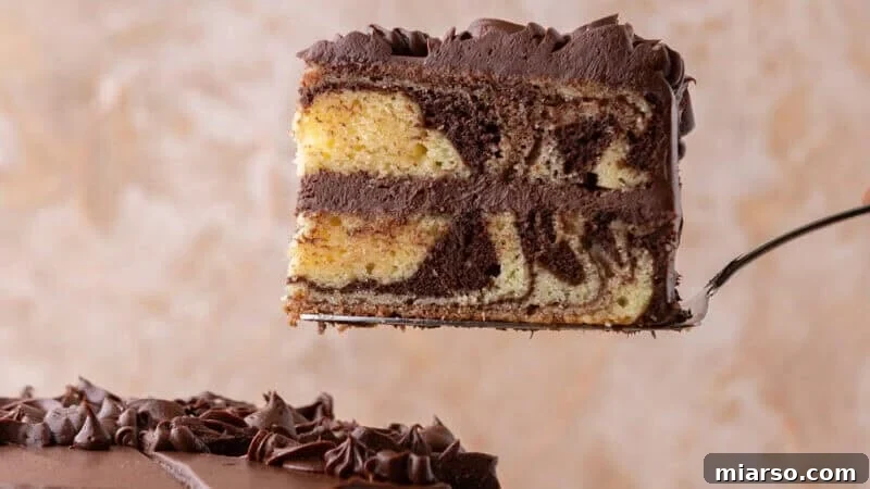 Ultimate Moist Marble Layer Cake with Rich Chocolate Cream Cheese Frosting 2 Slice of layered marble cake with chocolate cream cheese frosting lifted on a cake server showing vanilla and chocolate swirls