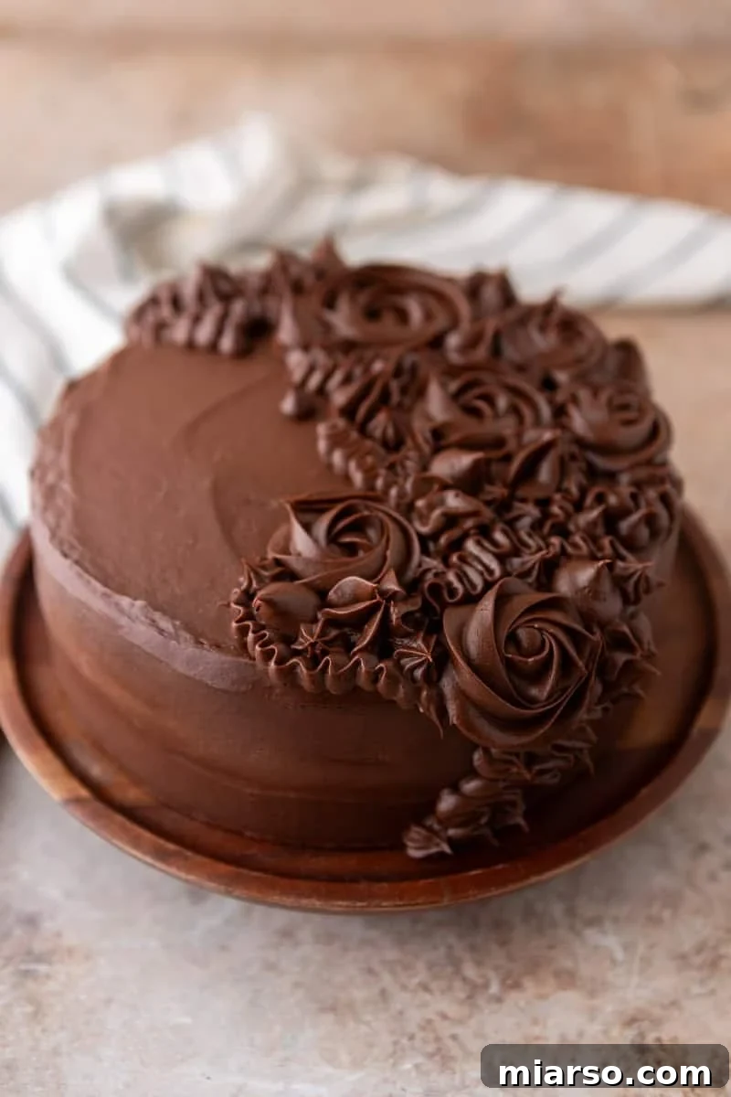 Ultimate Moist Marble Layer Cake with Rich Chocolate Cream Cheese Frosting 13 Finished layered marble cake frosted with chocolate cream cheese frosting and decorated with piped rosettes on a wooden plate