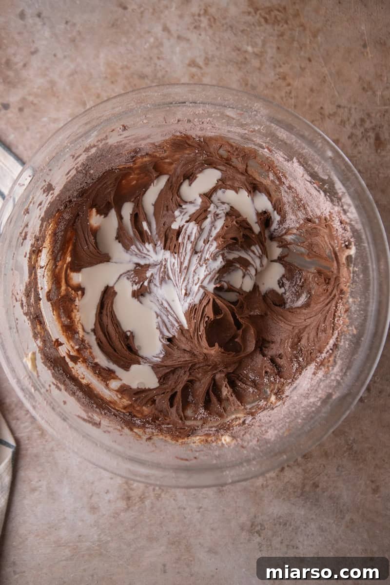 Velvety Chocolate Cream Cheese Indulgence 6 Heavy cream being added to the frosting while mixing in a glass bowl
