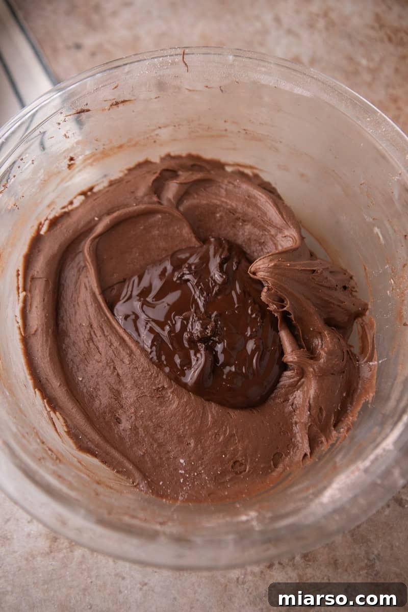 Velvety Chocolate Cream Cheese Indulgence 7 Melted dark chocolate added to the frosting in a glass bowl