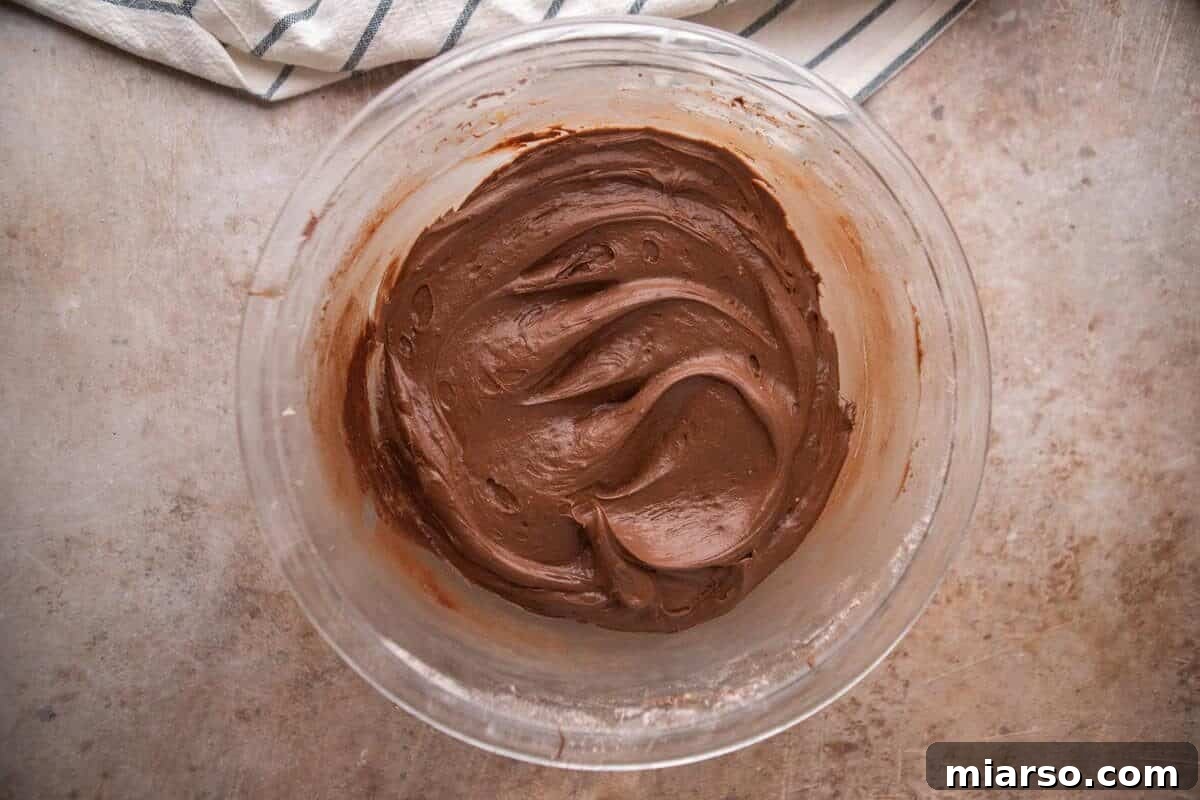 Velvety Chocolate Cream Cheese Indulgence 8 Smooth and creamy chocolate cream cheese frosting in a glass mixing bowl