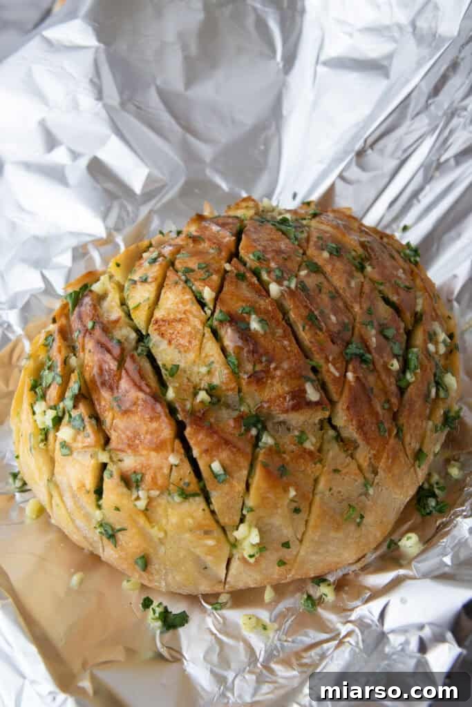 Sourdough loaf stuffed with garlic and wrapped in foil before baking
