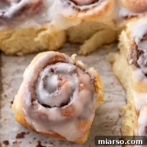 Single mini cinnamon roll with cream cheese glaze pulled from the pan showing soft texture