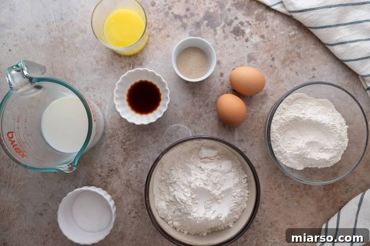 Ingredients for mini cinnamon roll dough including flour, bread flour, milk, melted butter, eggs, yeast, vanilla bean paste, and sugar