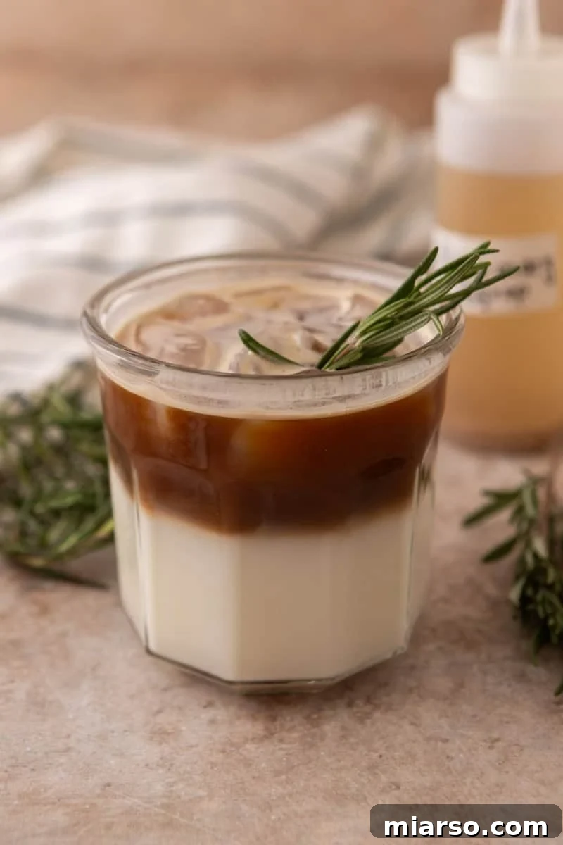 Layered rosemary latte with milk on the bottom and espresso poured over ice on top