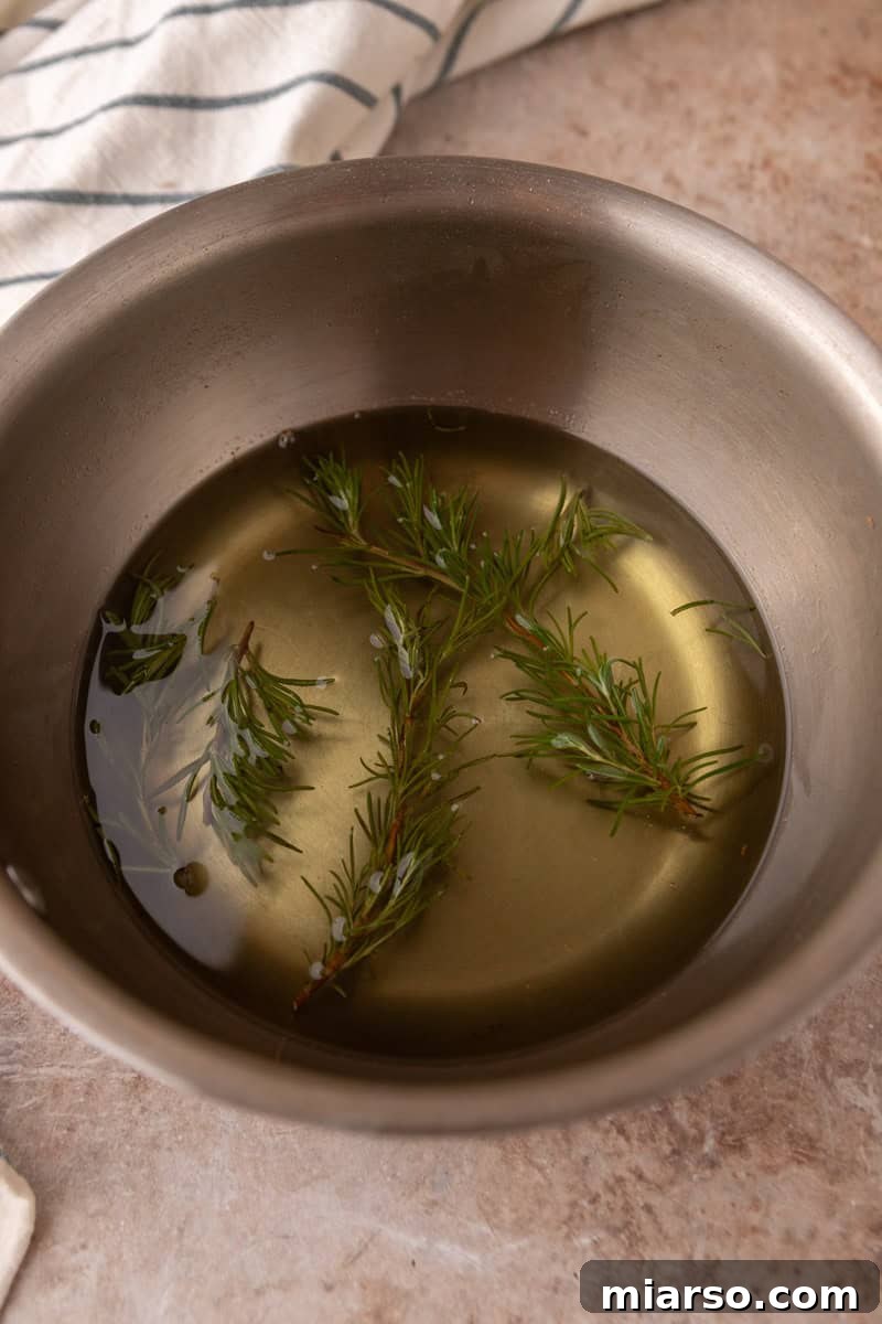 Finished rosemary simple syrup with steeped sprigs in a saucepan