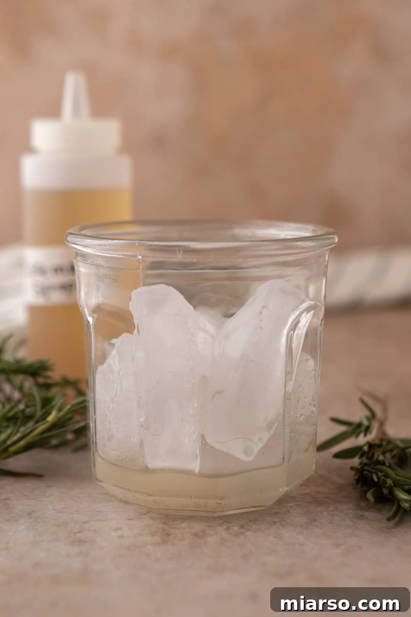  Glass filled with ice and a layer of rosemary vanilla syrup at the bottom