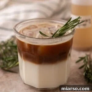 Layered rosemary latte with milk on the bottom and espresso poured over ice on top