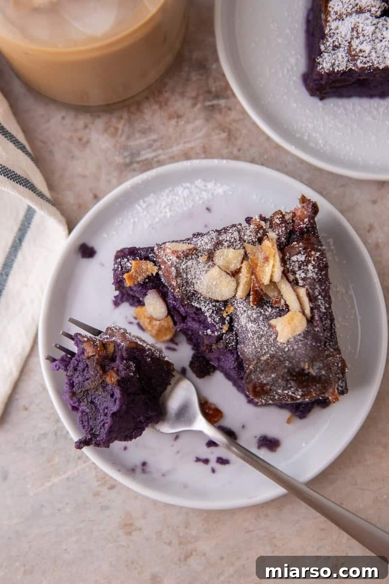 Overhead view of a slice of ube French toast bake on a white plate with a forkful pulled out