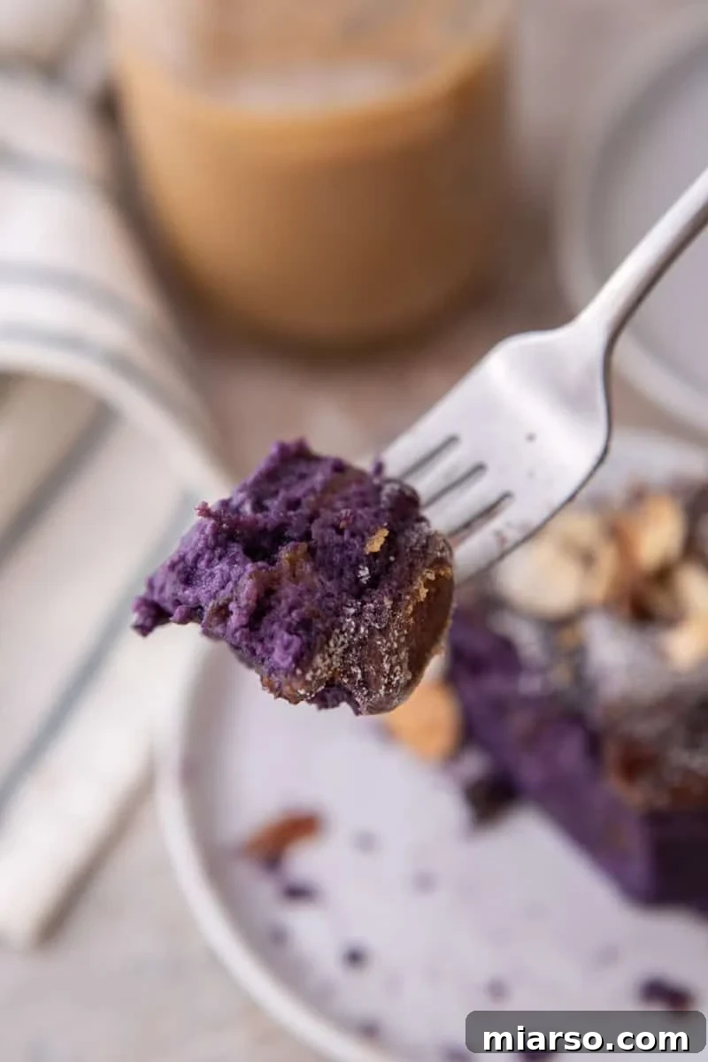 Close up of a forkful of soft purple ube French toast bake with coffee in the background
