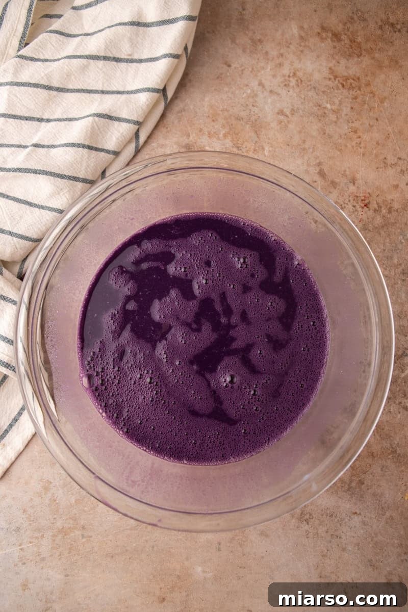 Vibrant purple coconut milk and ube custard whisked smooth in a glass bowl