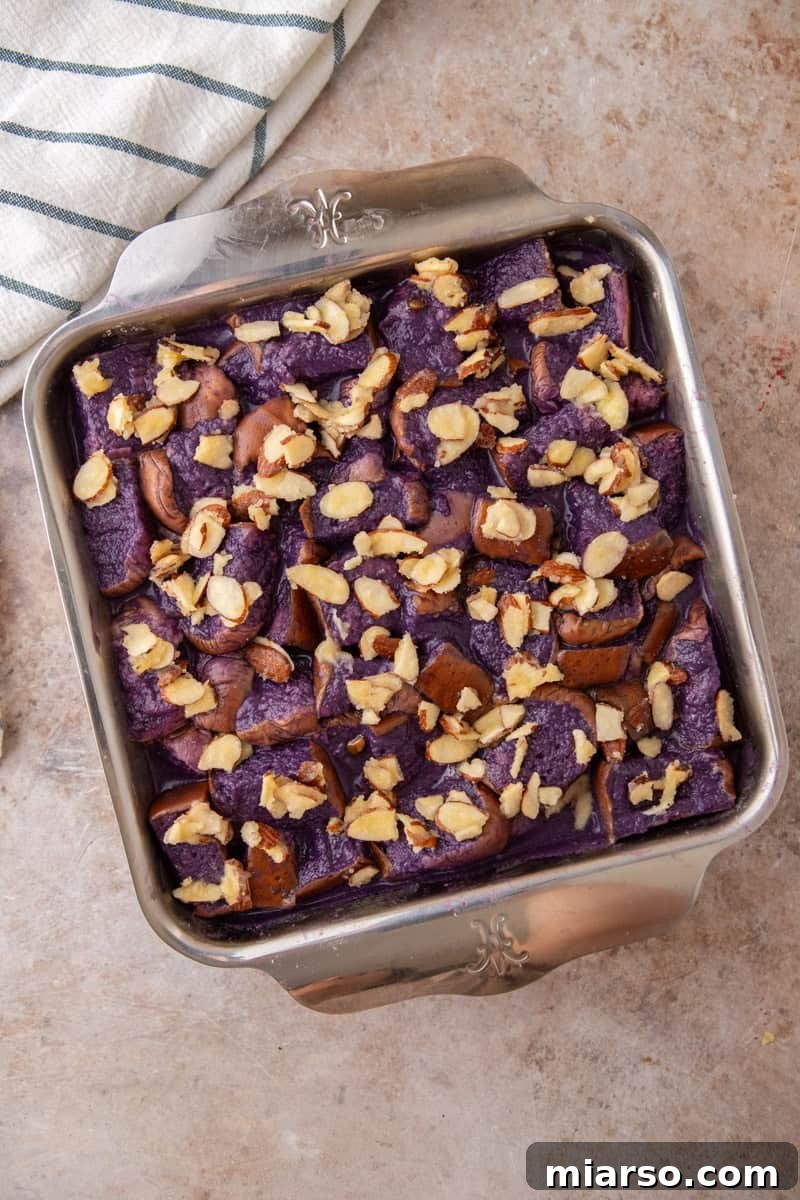 Soaked French toast bake topped with buttered sliced almonds and ready to go in the oven