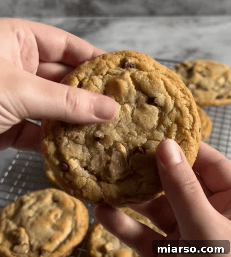 Close-up of a chocolate chip cookie being held over a cooling rack, a community bake from Loaf BakeClub