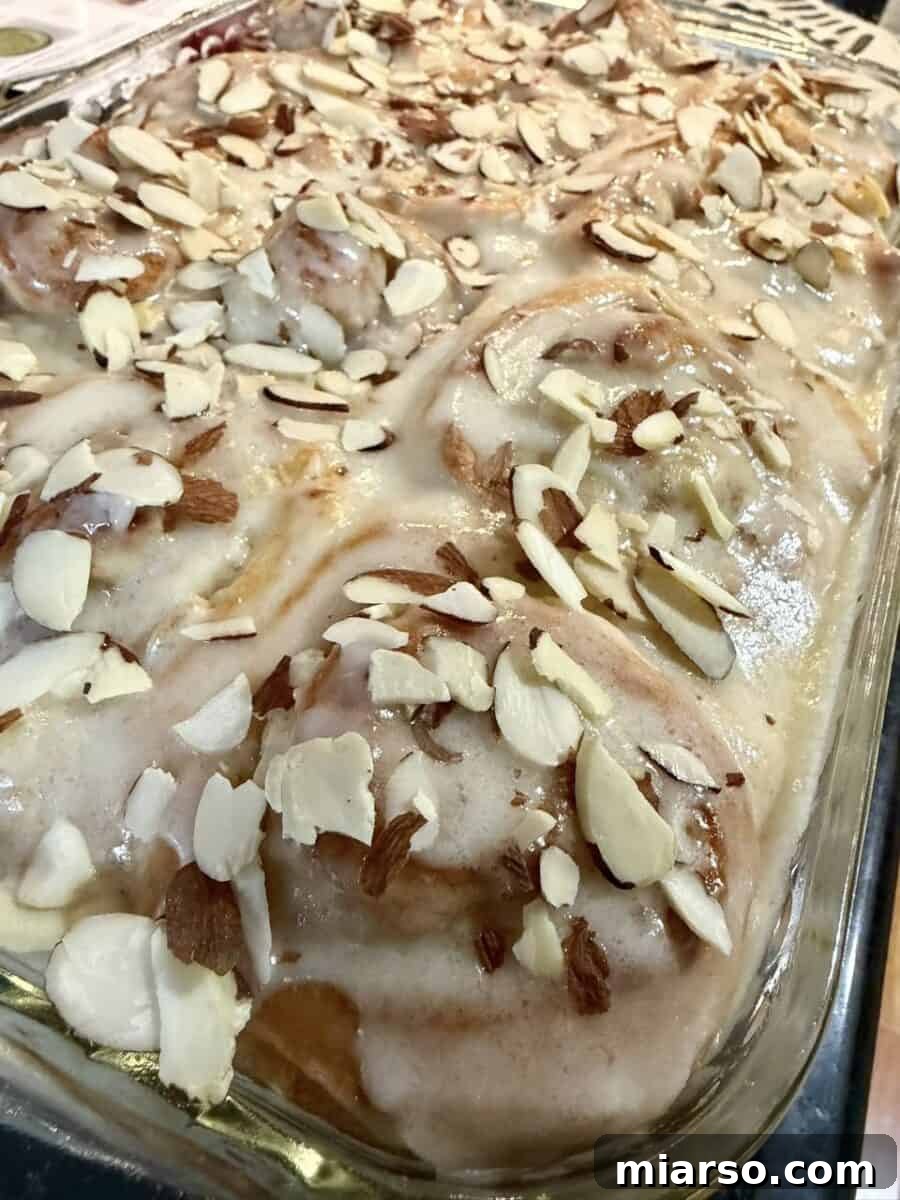 Glazed almond cinnamon rolls topped with sliced almonds, a past Loaf BakeClub featured recipe