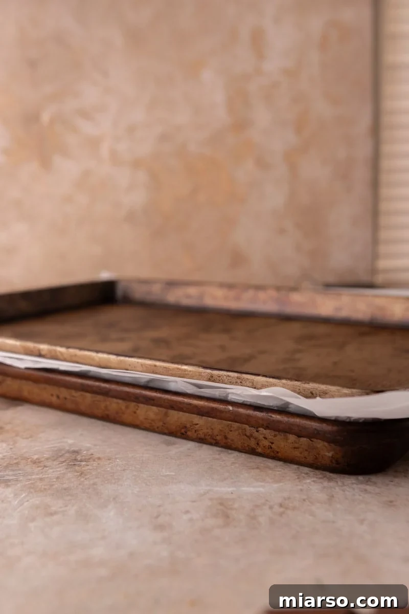 Two baking sheets stacked with parchment between to press croissants flat for croissant Christmas crack