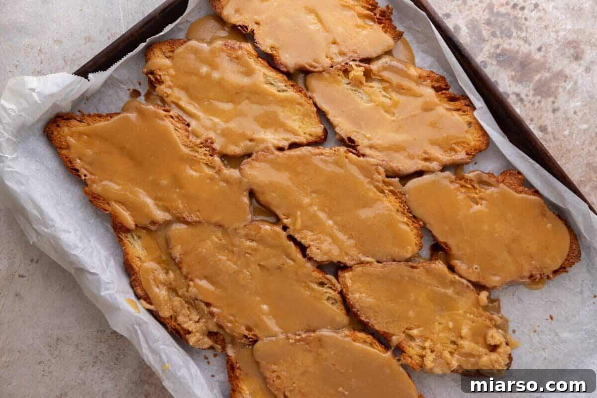 Brown sugar toffee spread over toasted pressed croissants on a parchment-lined sheet pan
