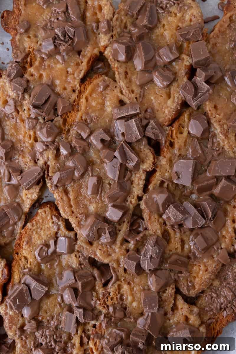Chopped chocolate scattered over brown sugar toffee on pressed croissants for Christmas crack