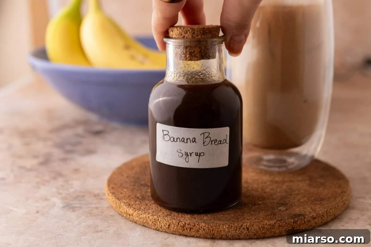 Hand placing a cork stopper on a glass bottle of homemade banana bread syrup