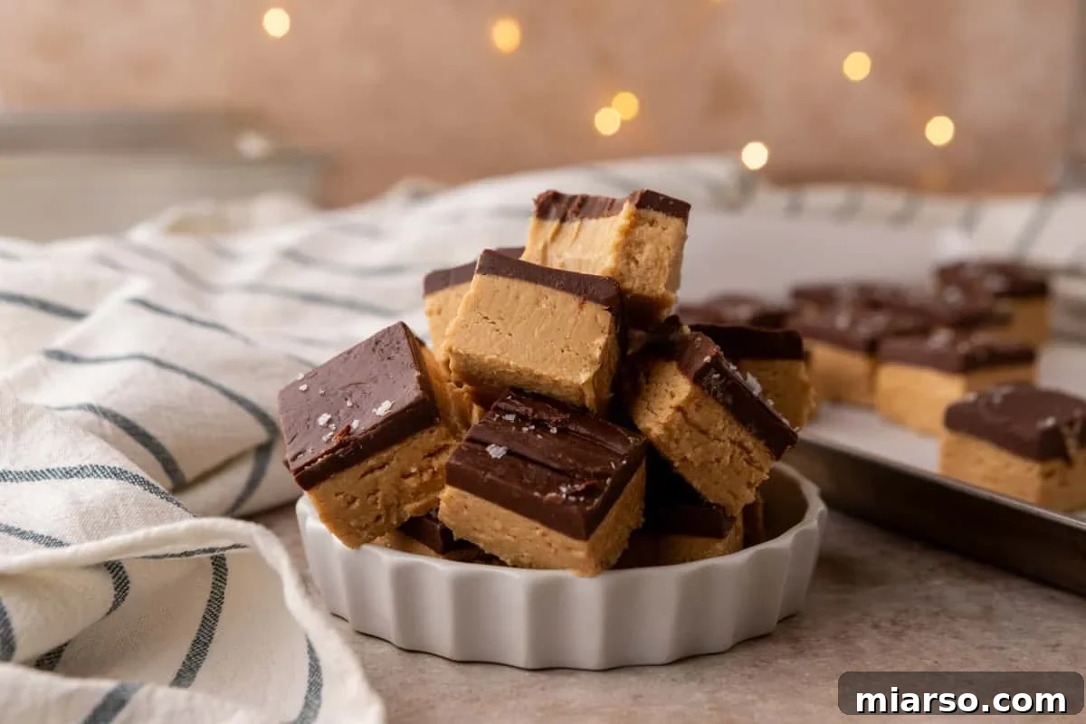 Buckeye fudge squares stacked in a white fluted dish topped with flaky salt