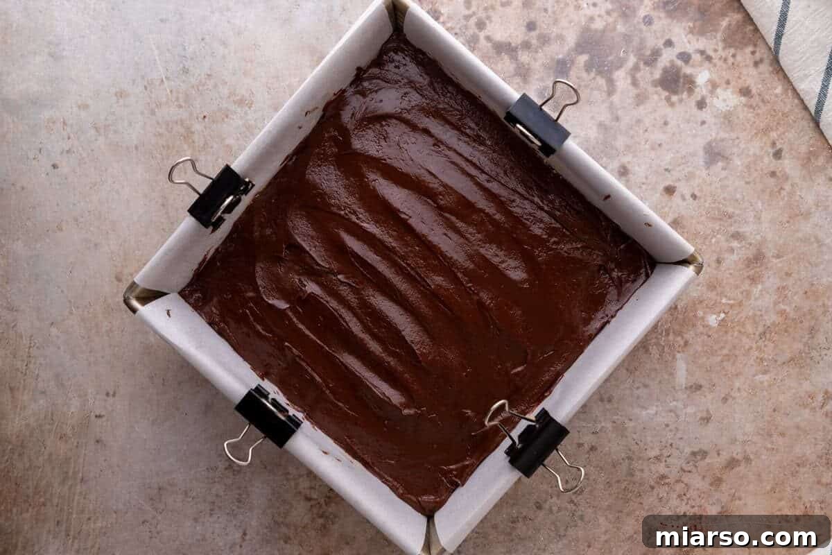 Melted chocolate spread over the peanut butter layer in a parchment lined pan