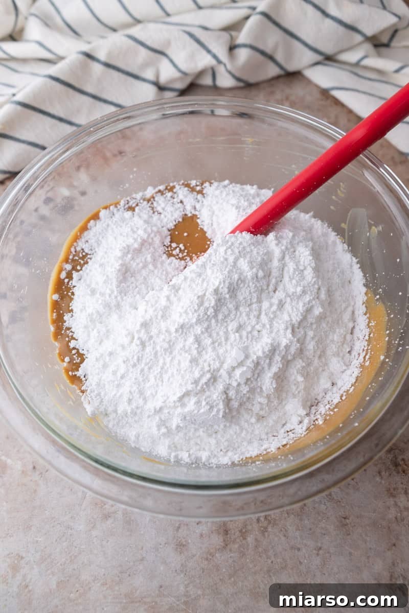 Powdered sugar added to the peanut butter mixture in a glass bowl