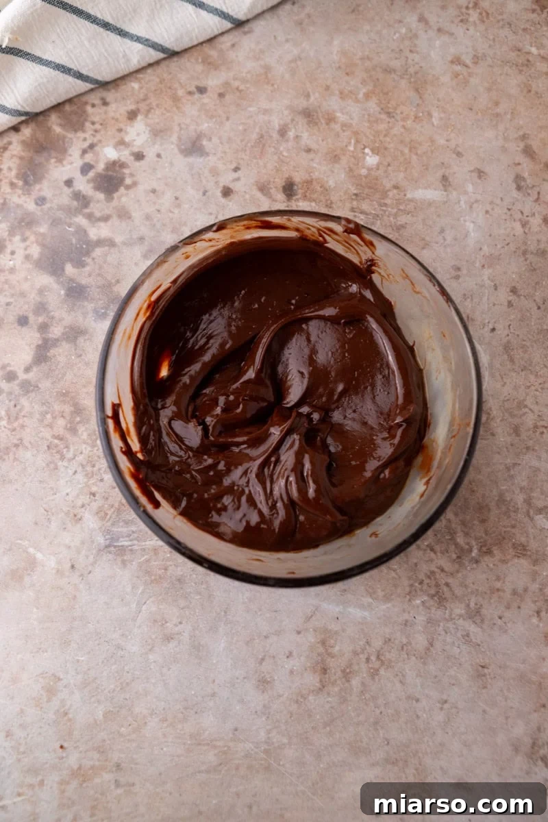 Smooth melted chocolate ganache in a glass bowl