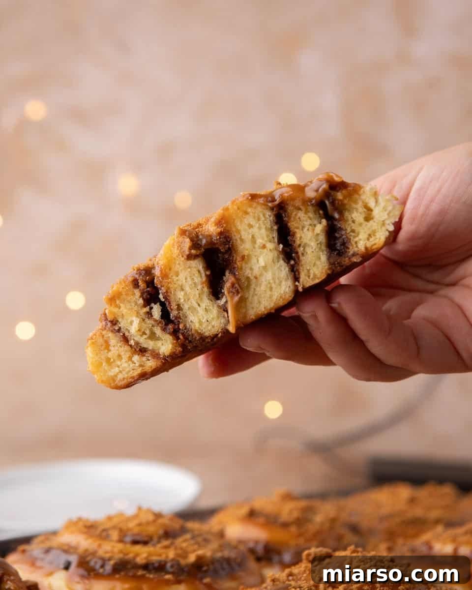 Hand holding half a cookie butter cinnamon roll showing the soft, layered tangzhong brioche crumb
