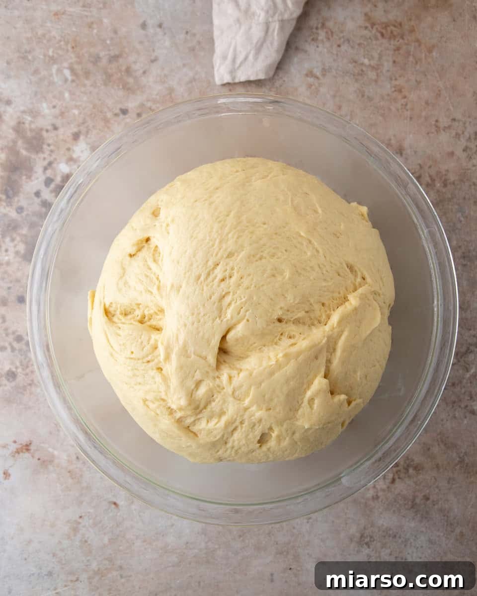Brioche dough doubled in size in a glass bowl after the first rise