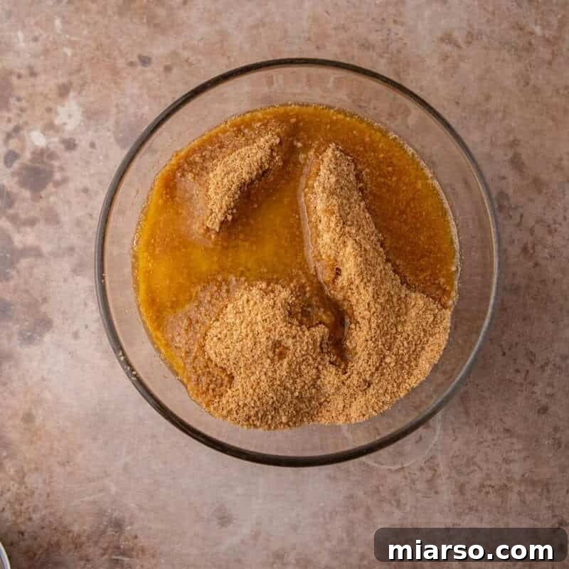 Graham cracker crumbs and melted butter being stirred together to form the crust
