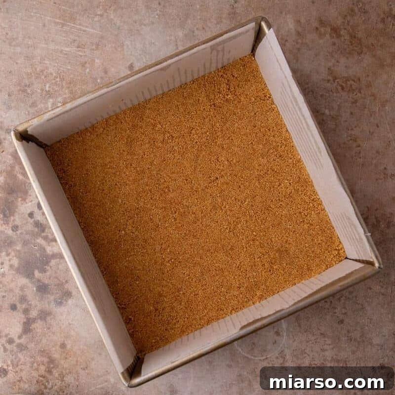 Graham cracker crust pressed evenly into a parchment-lined 8x8 pan 