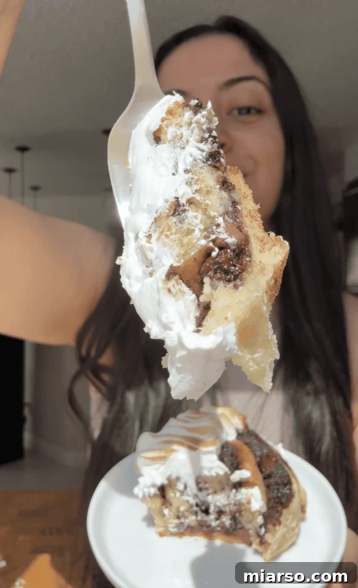 Forkful of a s'mores cinnamon roll with gooey chocolate and toasted meringue held over a plate