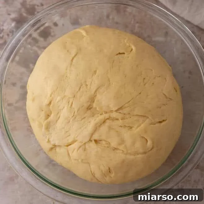 Brioche dough doubled in size in a glass bowl after the first rise