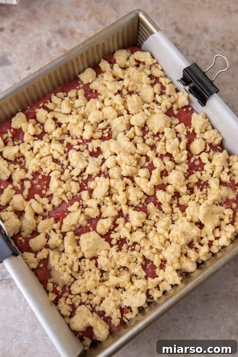 Tangy Rhubarb Crumble Bars with Oat Streusel 11 Shortbread crumble topping scattered over the rhubarb filling in the 8x8 baking pan, ready to bake