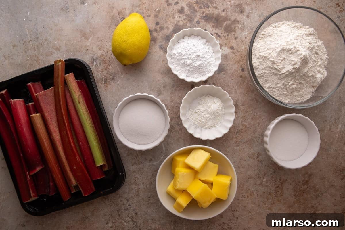 Tangy Rhubarb Crumble Bars with Oat Streusel 3 Overhead flat lay of rhubarb crumble bar ingredients including fresh rhubarb stalks, cubed butter, flour, powdered sugar, granulated sugar, cornstarch, and a lemon