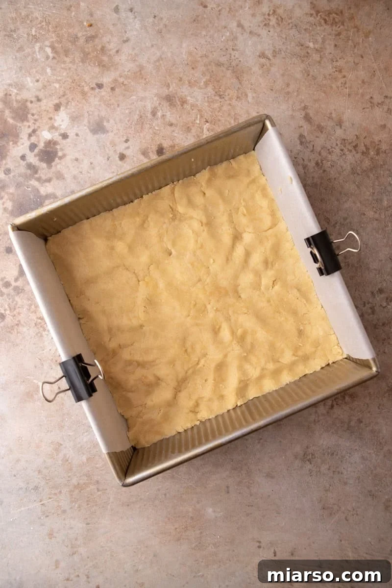 Tangy Rhubarb Crumble Bars with Oat Streusel 8 Shortbread dough pressed evenly into the bottom of a parchment-lined 8x8 gold baking pan before par-baking