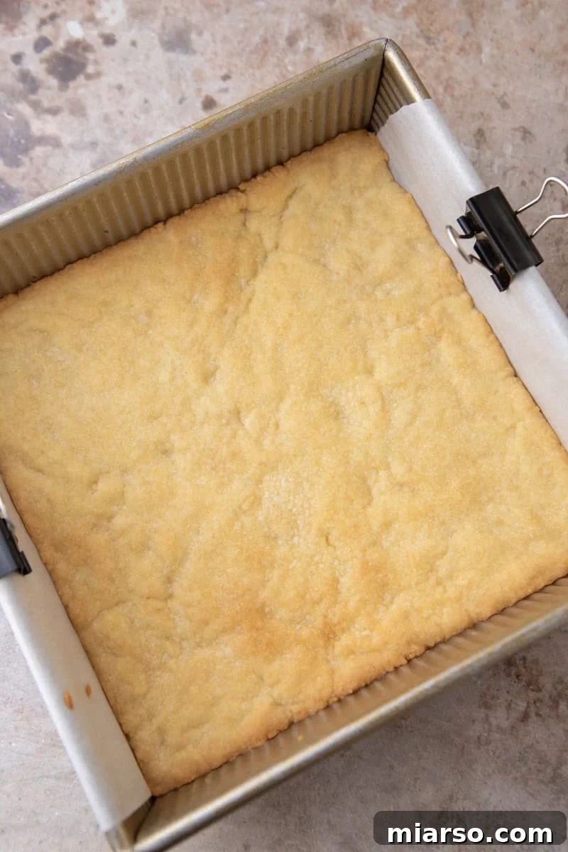 Tangy Rhubarb Crumble Bars with Oat Streusel 9 Par-baked shortbread crust in an 8x8 gold baking pan, golden and set, fresh out of the oven