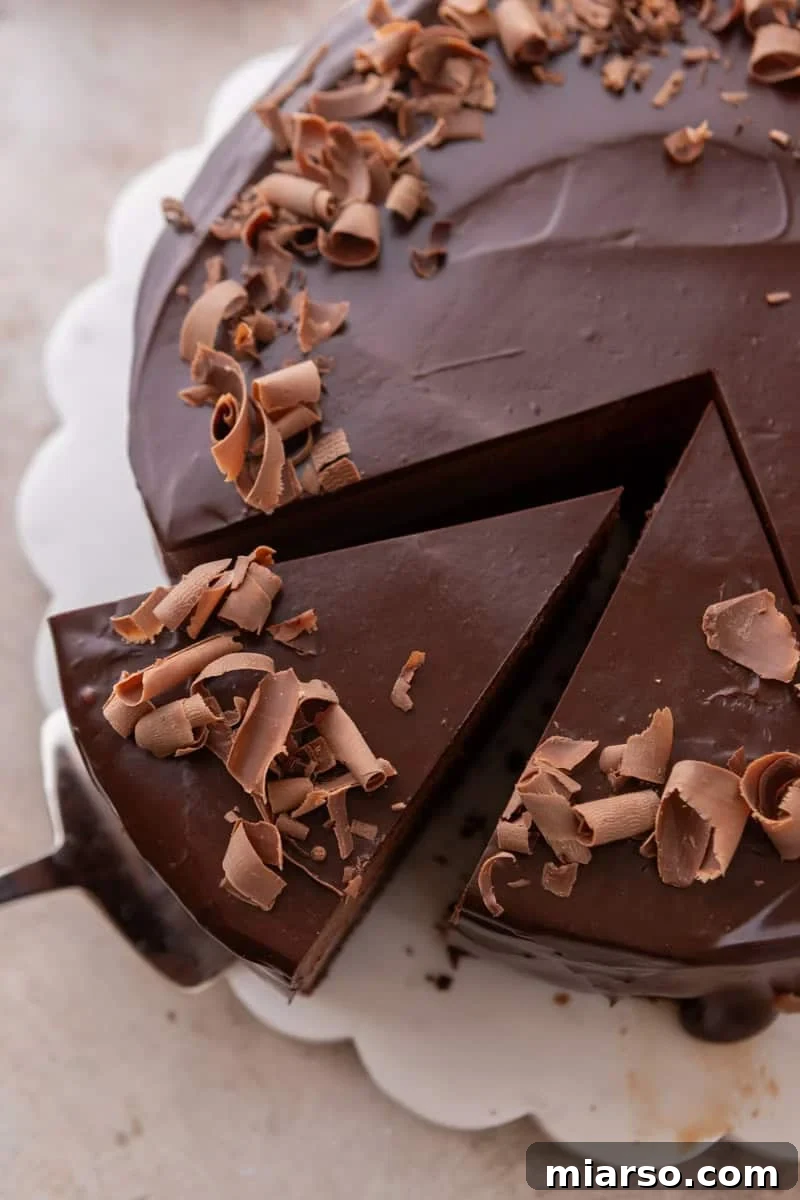 Decadent Chocolate Mousse Cake Recipe 15 Overhead view of mousse cake topped with chocolate curls, with one slice being lifted out by a cake server