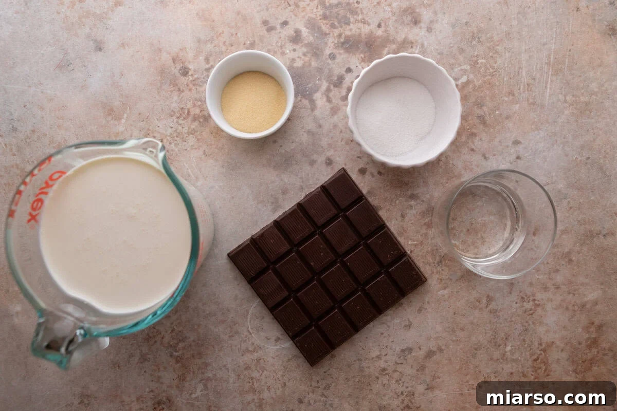 Decadent Chocolate Mousse Cake Recipe 4 Ingredients for the chocolate mousse layer including heavy cream in a measuring cup, a dark chocolate bar, powdered beef gelatin, sugar, and cold water