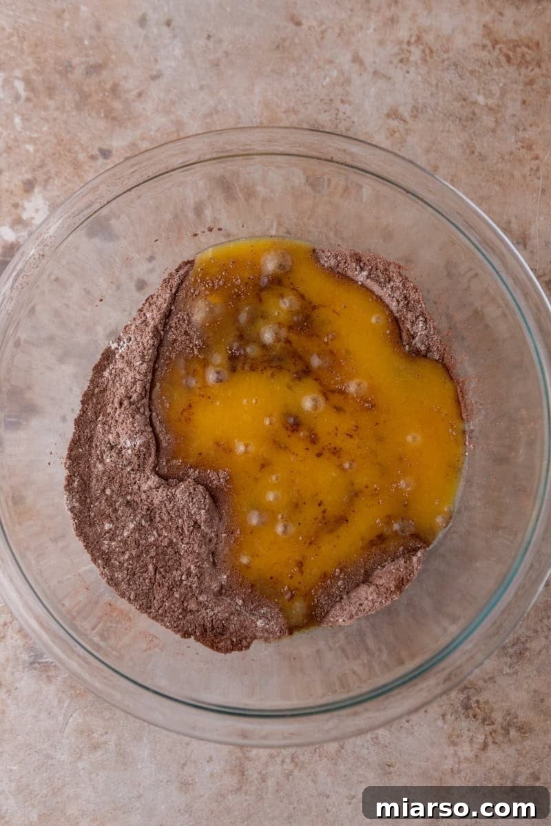 Decadent Chocolate Mousse Cake Recipe 7 Wet ingredients poured over the dry cocoa powder and flour mixture in a glass mixing bowl