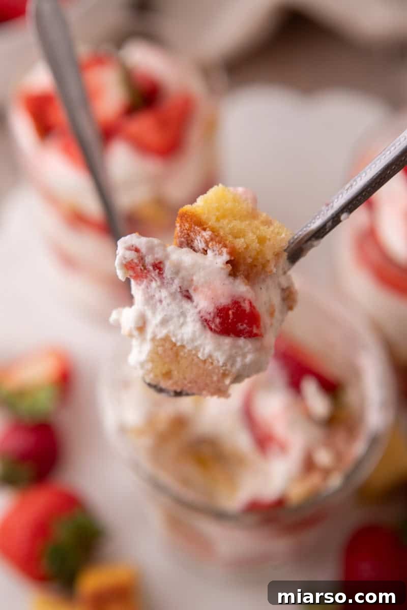 Mini Strawberry Shortcake Trifle Cups Recipe 11 A spoonful of strawberry shortcake trifle with vanilla cake, whipped cream, and juicy strawberries lifted from the glass