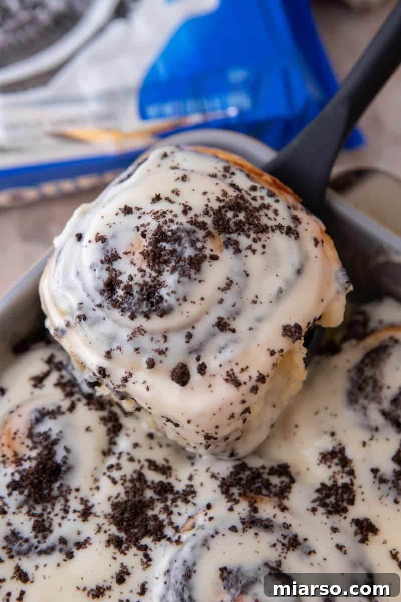 Oreo-Stuffed Cinnamon Rolls with Cream Cheese Glaze 12 Glazed Oreo cinnamon roll topped with crushed Oreos being lifted from the pan
