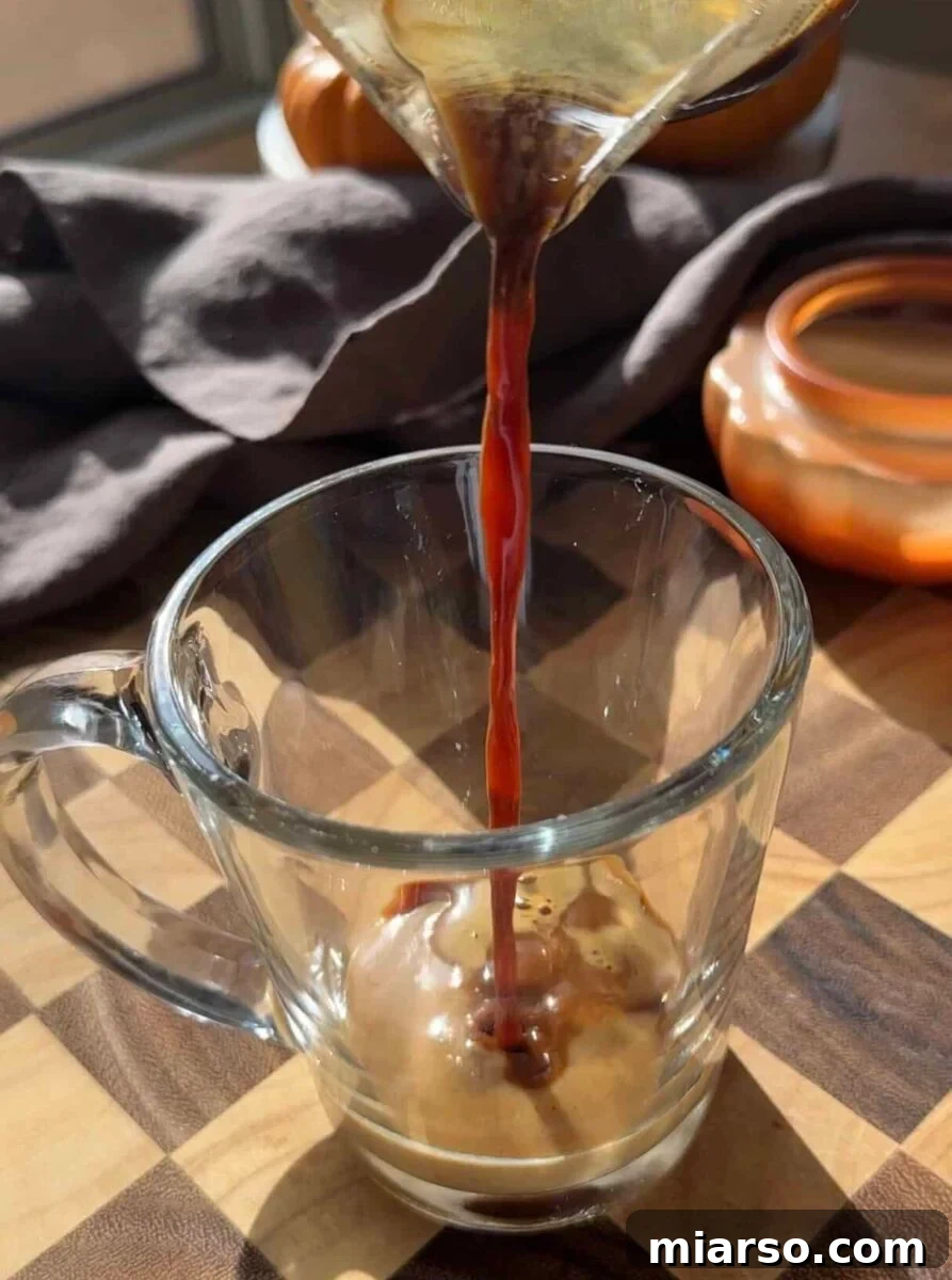 Make a Copycat Starbucks Pumpkin Spice Latte at Home 5 Hot espresso poured over two tablespoons of pumpkin spice sauce in a tall glass mug.