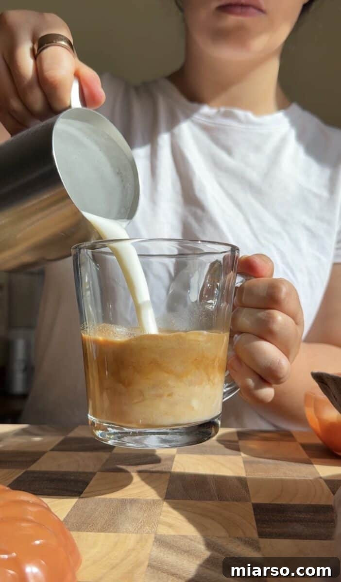 Make a Copycat Starbucks Pumpkin Spice Latte at Home 6 Steamed milk poured into a mug of pumpkin spiced espresso to build the latte.